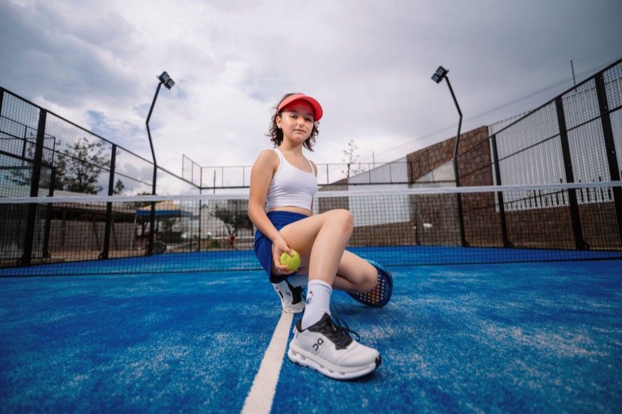 Junior padel player sitting on an outdoor padel court