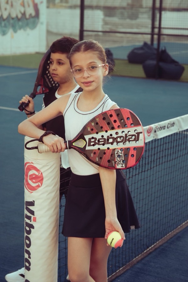 Two children playing padel on an outdoor court