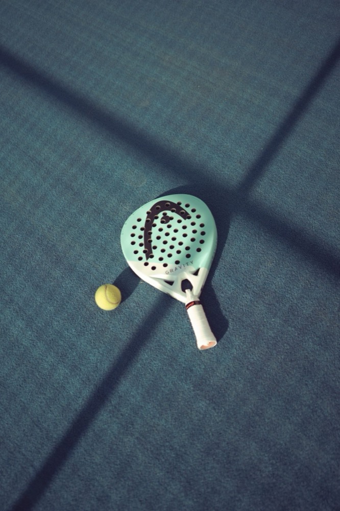 Padel racket and ball on a sunlit court